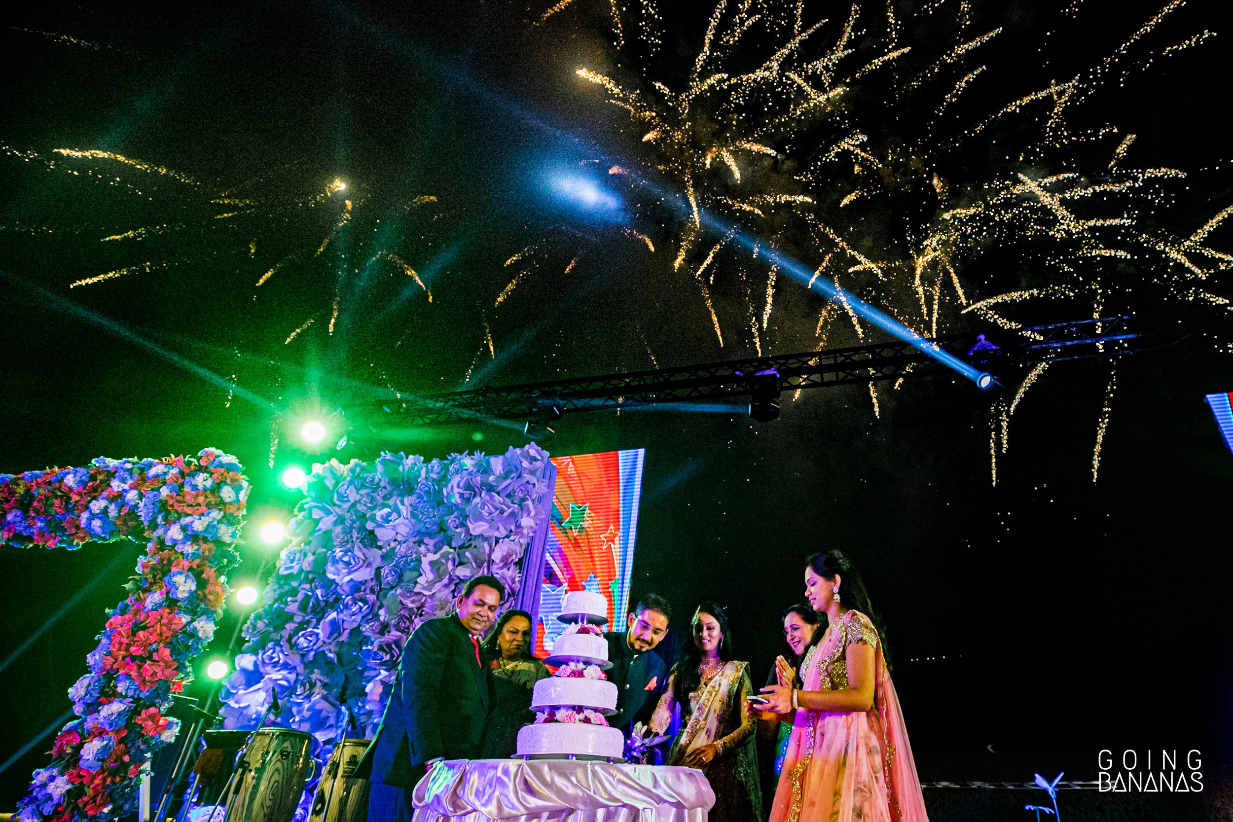 The bride and the groom with family cutting a cake against a backdrop of fireworks at Marriott Rayong Thailand