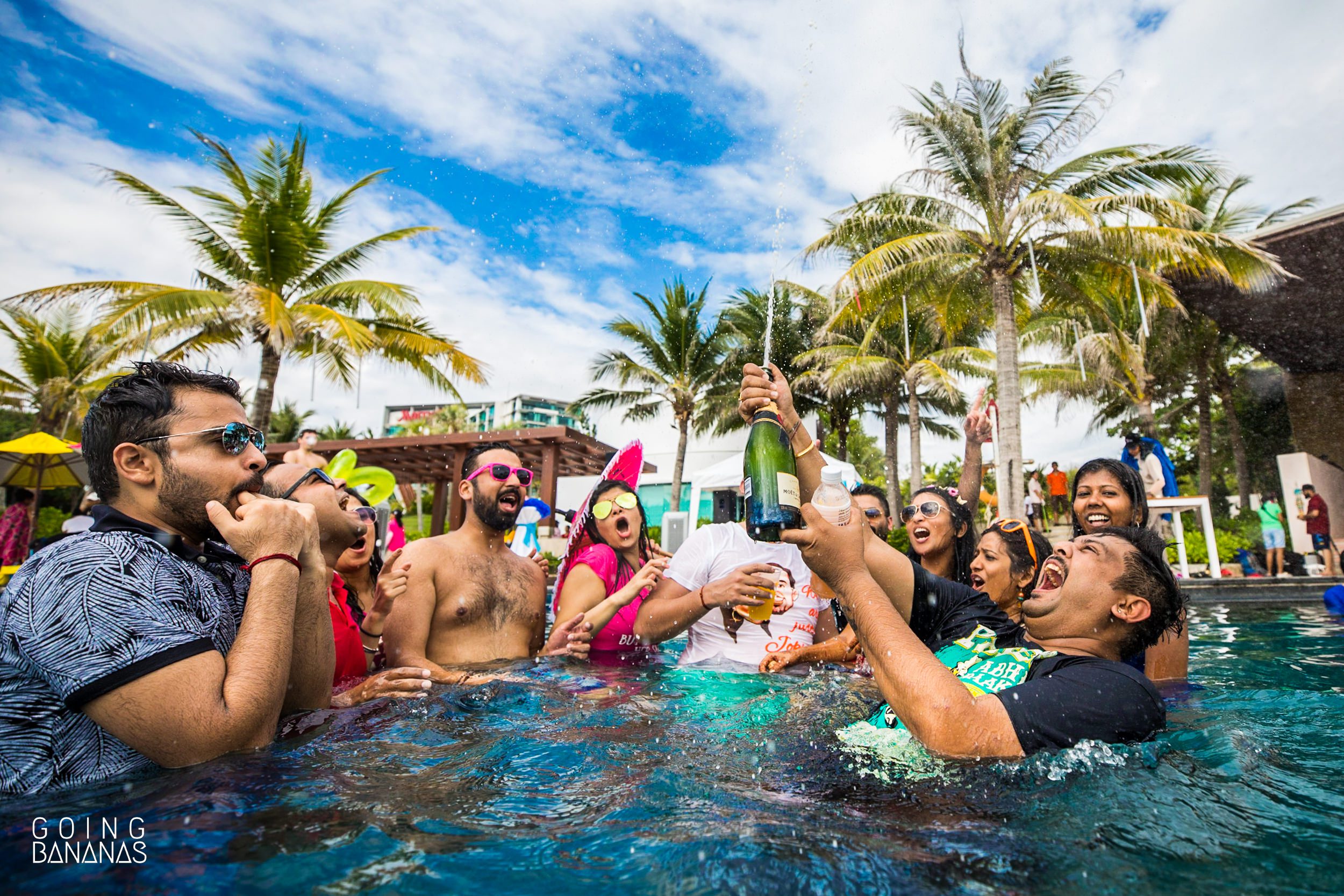 Friends and family of the bride and groom celebrating with a bottle of champagne in the pool at Marriott Rayong Thailand