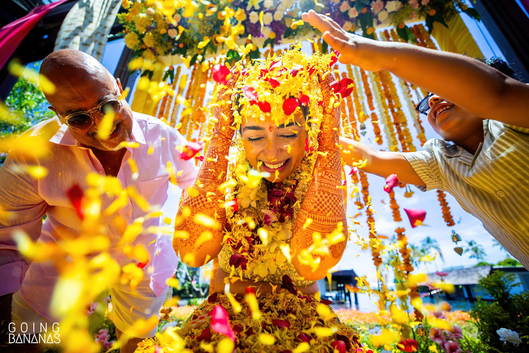 Friends showering the bride with flower petals during her haldi at JW Marriott Khao Lak Thailand